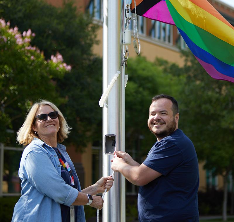 Two 澳门正规博彩十大排行平台 employees raise the Pride flag at the company's San Rafael campus.